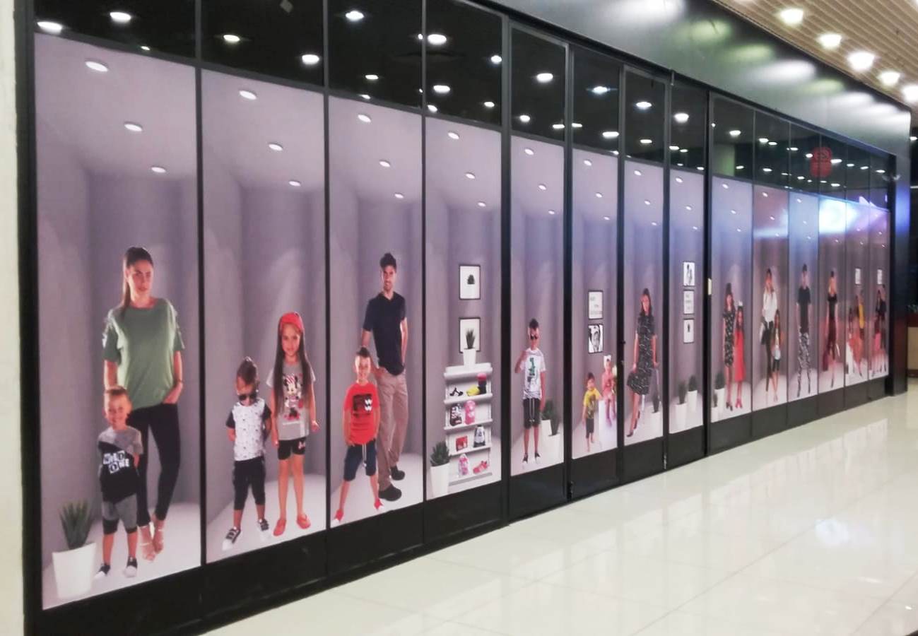 תמונה של ויטרינה של חנות בגדים שרואים בה כל מיני תמונות של ילדים גברים ונשים כדי להראות קולקציה להמחשה