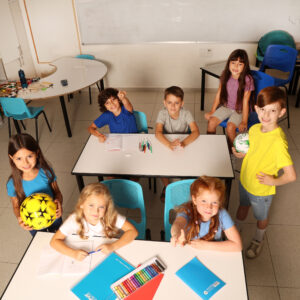 שבועה ילדים תלמידים בכיתה יושבים ומסתכלים ארבע ילדות שלושה בנים. הילדות לובשות חולצות לבנות כחולות וורודה הילדים צהוב אפור וכחול