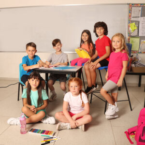 ילדים יושבים בכיתה לובשים חולצות בית ספר ורוד אדום כתום לבן כחול ואפור יש ארבע בנות שלושה בנים שתי בנות יושבות על הרצפה ויש טושים