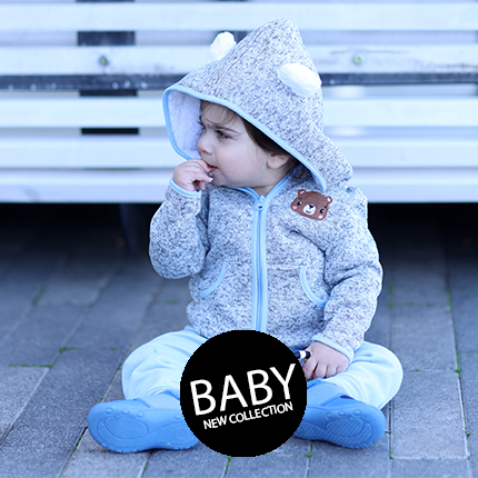 תינוק יושב על הרצפה לובש אוברול חם חורפי עם קפוצ'ון בצבע אפור מאחוריו גדר לבנה ורשום באמצע תינוק באנגלית BABY