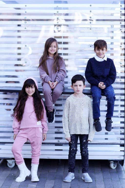 ארבעה ילדים בתמונה שניים יושבים על הגדר לובשים בגדי חורף חליפות