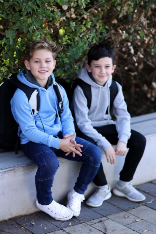שני ילדים לובשים קפוצון כחול ואפור עם תיק גב