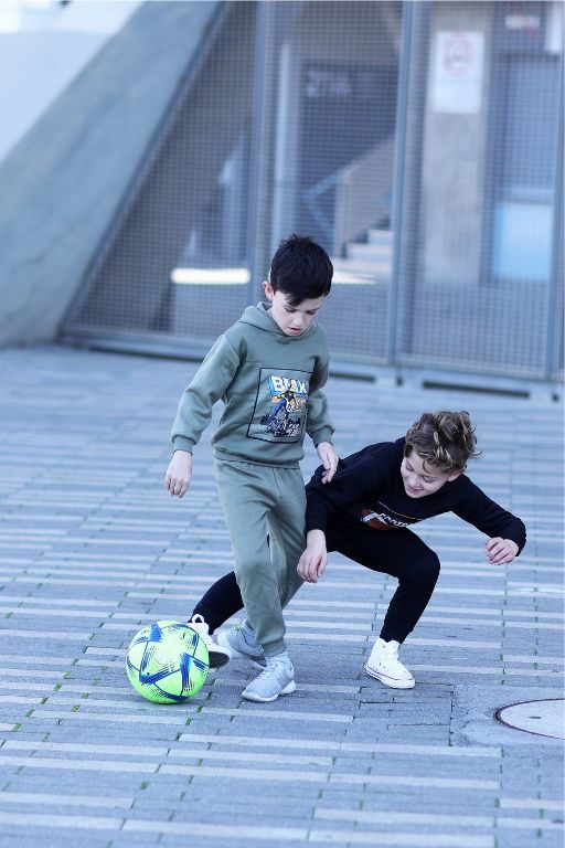 שני ילדים בחליפה של חורף משחקים כדורגל בכדור ירוק